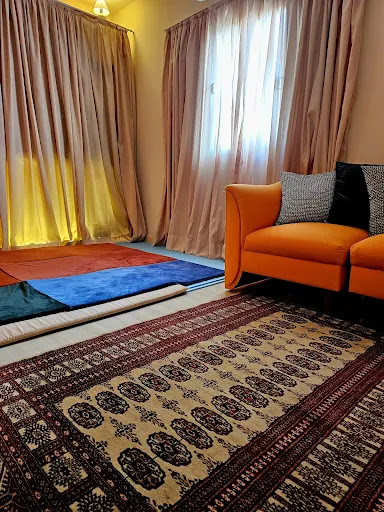 Ambiente de consultório para terapia psicocorporal e morfoanalítica no Espaço Presente, com sofá laranja, tapete e tatame para práticas corporais.Sala de terapia psicocorporal para sublocação.